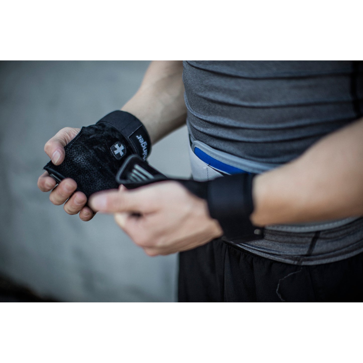 Person adjusts a fitness tracker on their wrist in a gym or fitness environment.