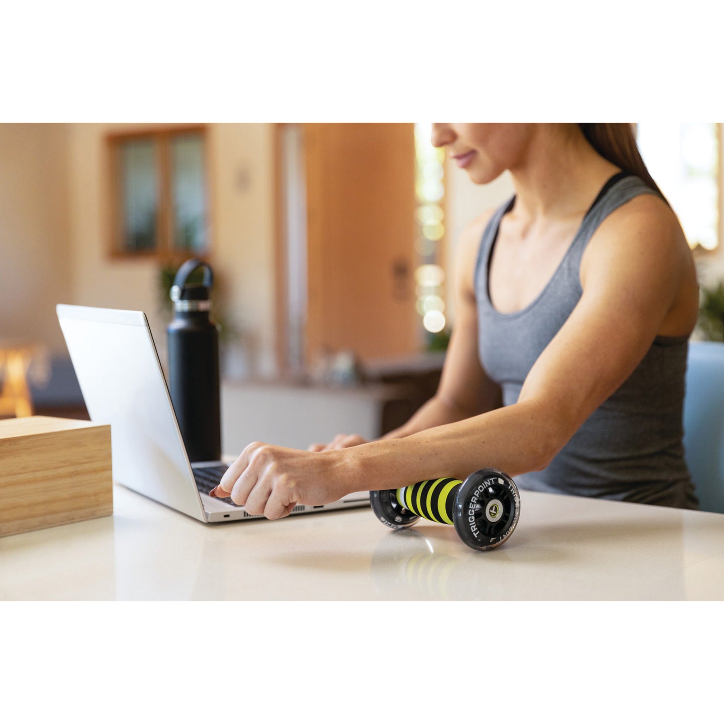 Woman using a laptop with a roller on a kitchen counter in a home environment