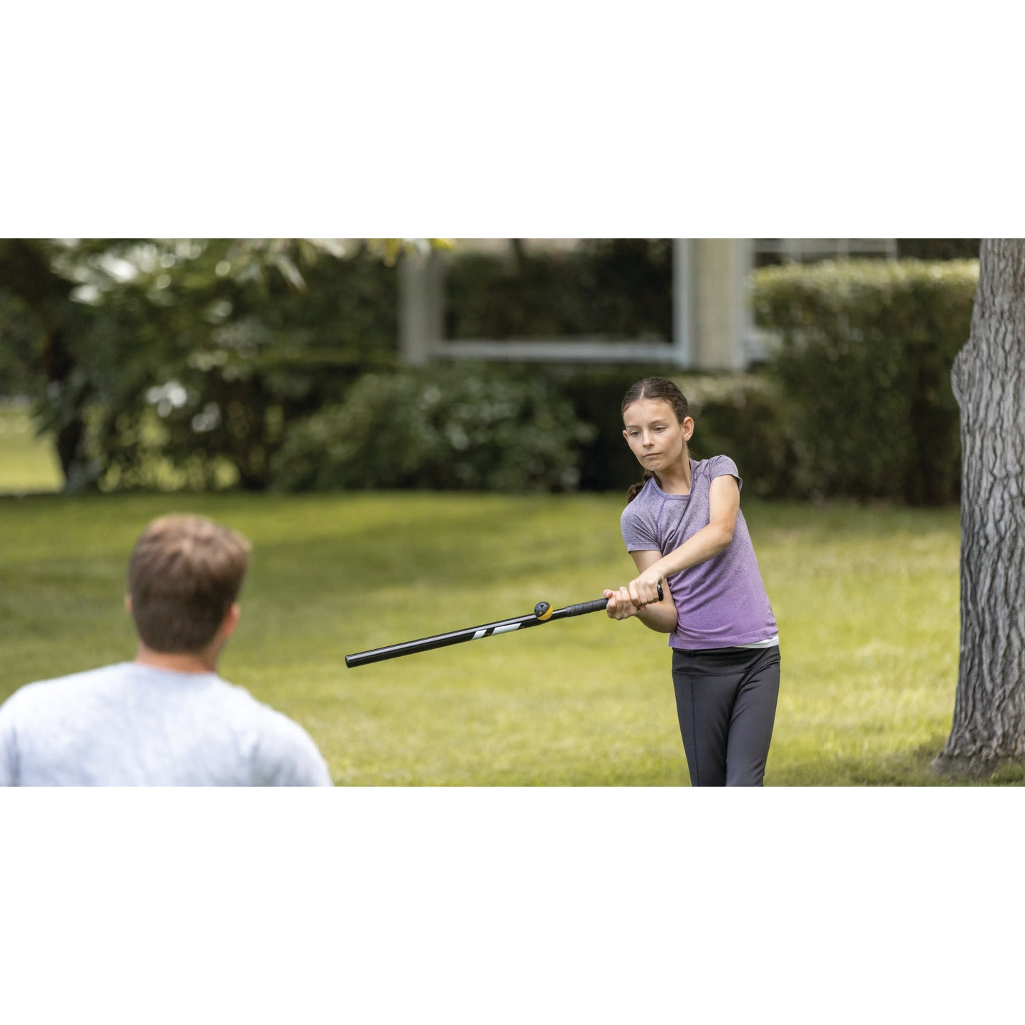 Girl swings bat at boy in backyard during daytime