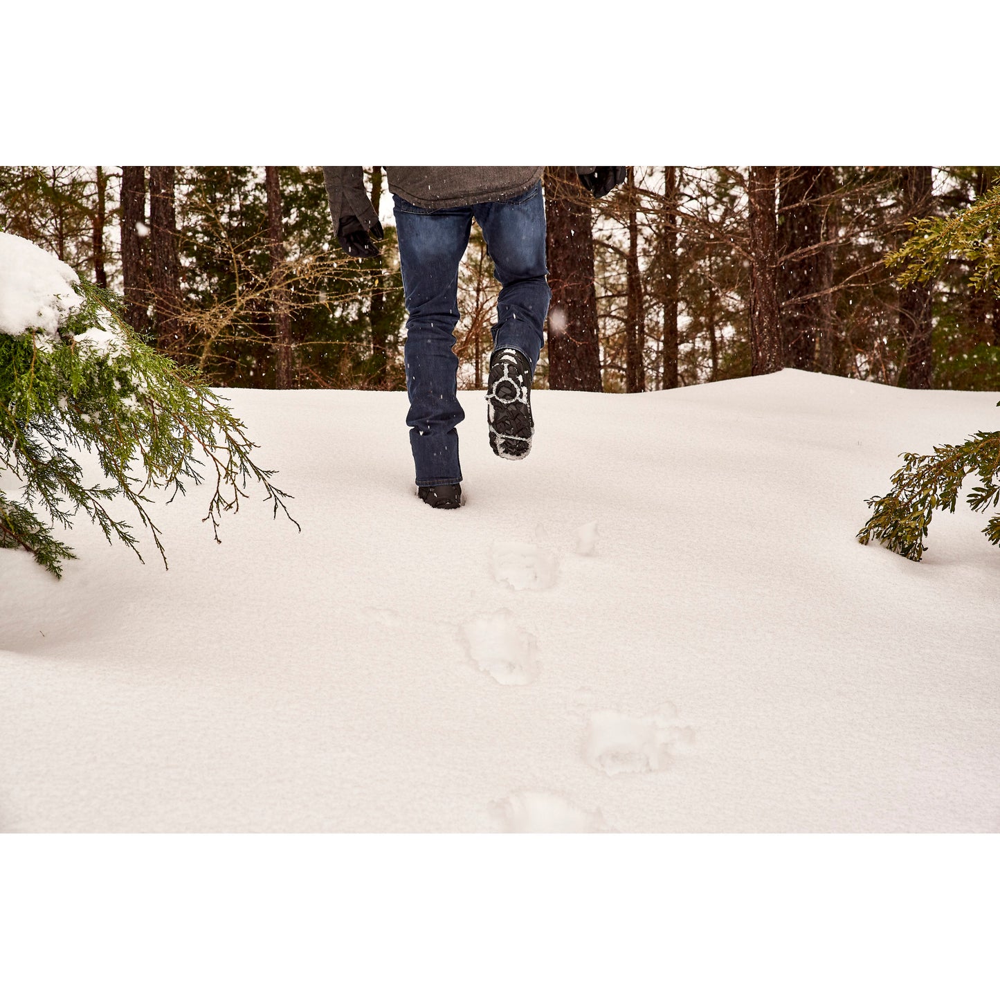 Person walks through snow in a forest during winter