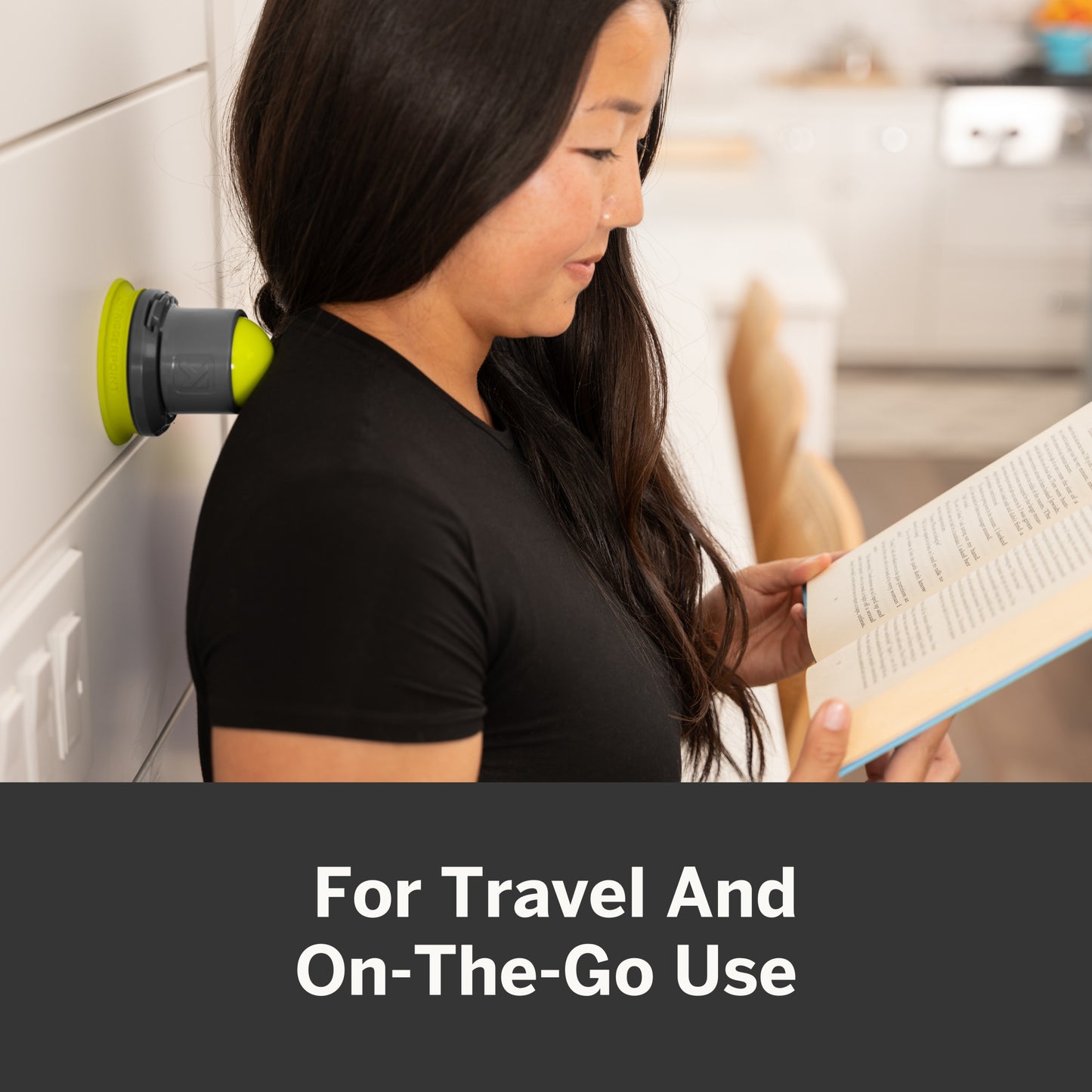 Woman reads book near wall hook with speaker for travel and on-the-go listening.