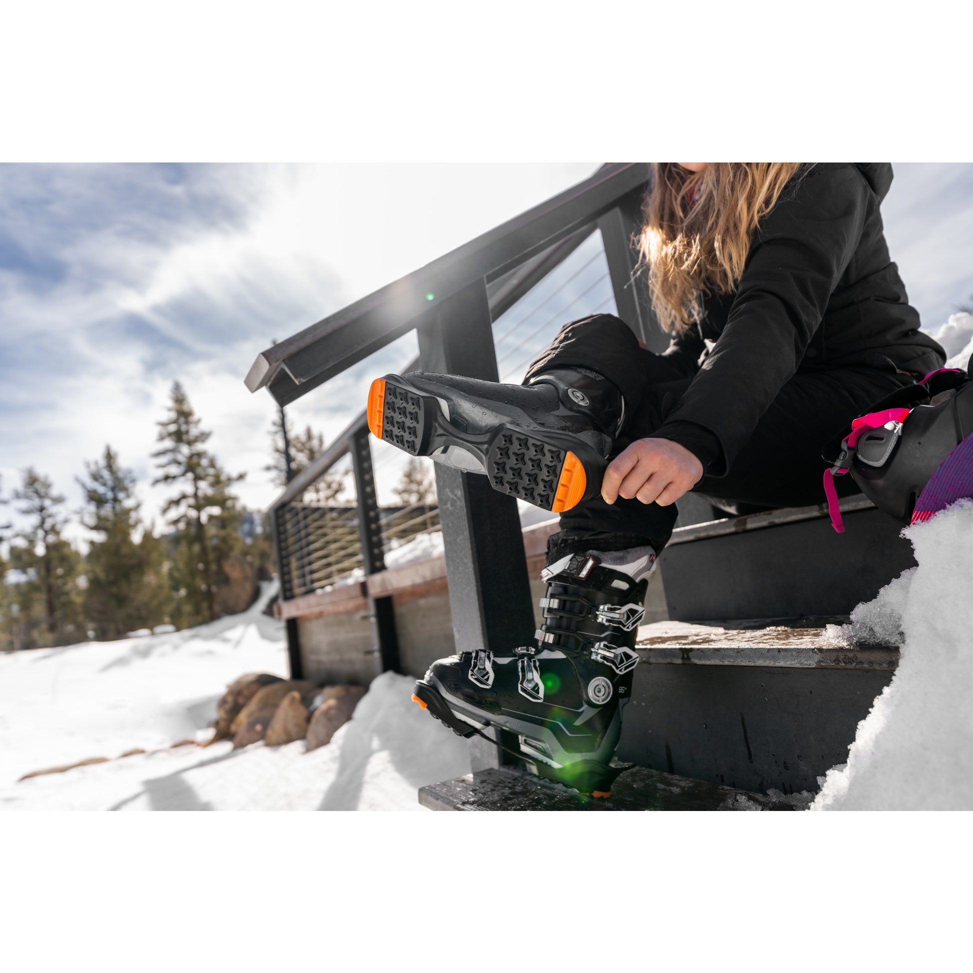 Child putting on ski boots on a snowcovered outdoor staircase during daytime
