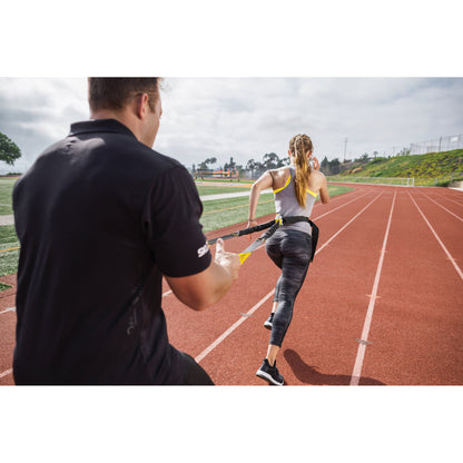 Female athlete using SKLZ Acceleration Trainer with a coach on a track