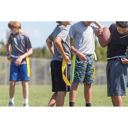 Children practice football drills on a grassy field during daytime outdoor sports activity