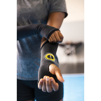 Person adjusts a sports elbow brace in a gym environment