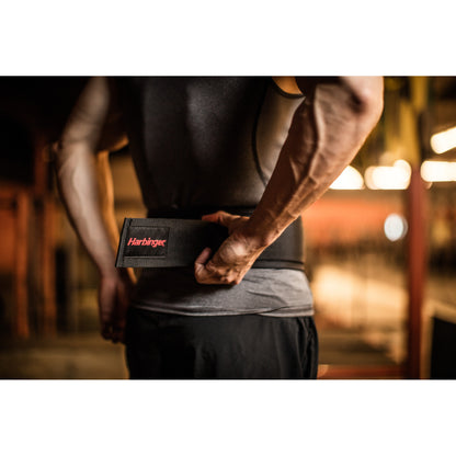 Person securing a weightlifting belt around their waist in a gym environment.