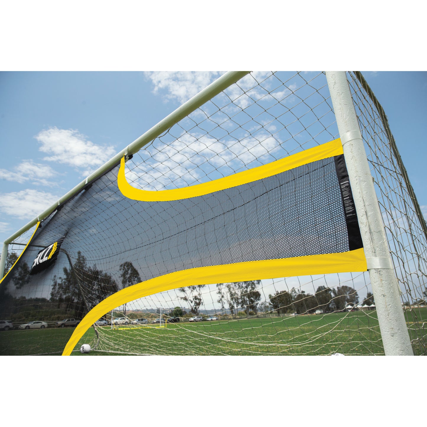 A soccer goal net is partially torn on a sports field under a blue sky