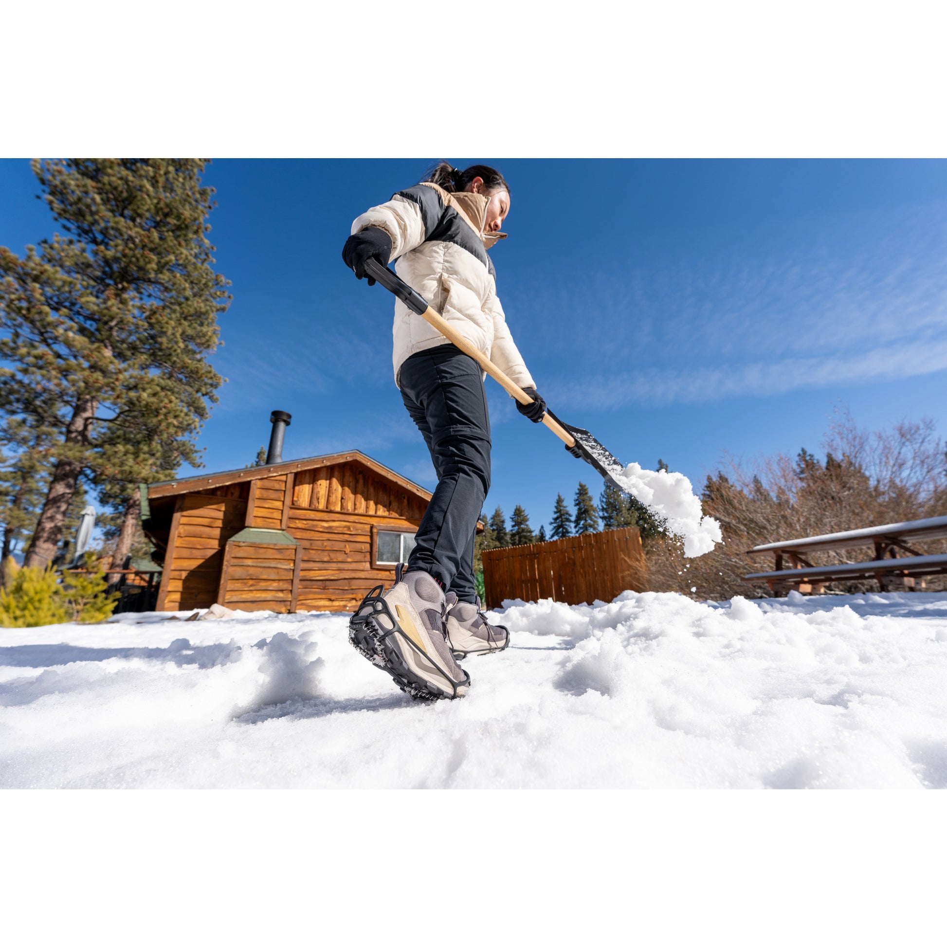 Person shoveling snow in a backyard during daytime
