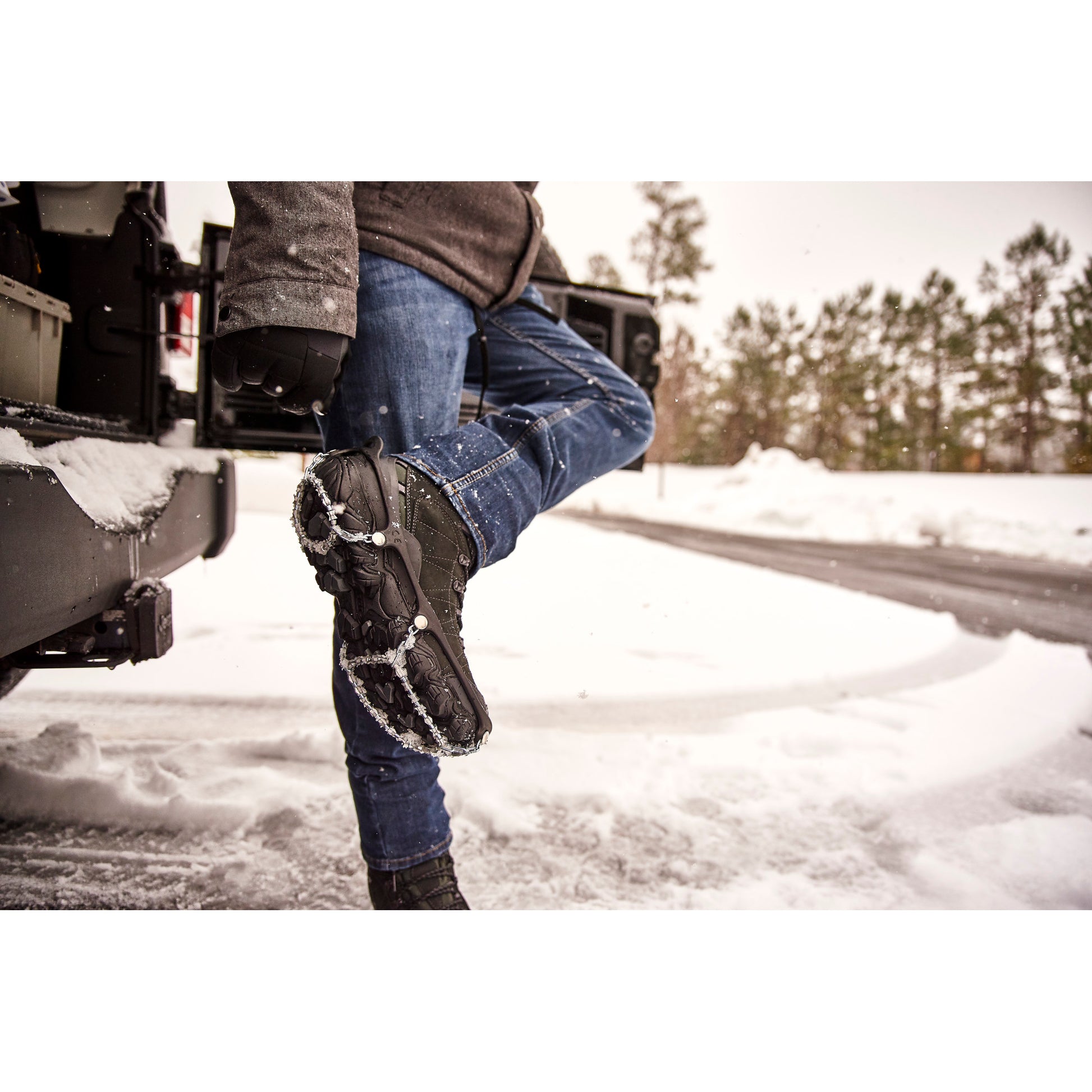 Person adjusts snowshoes on snowy ground outside in winter environment