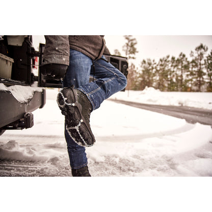 Person adjusts snowshoes on snowy ground outside in winter environment