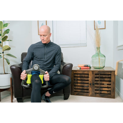Man exercises with a pedal machine on a brown leather sofa in a cozy living room.