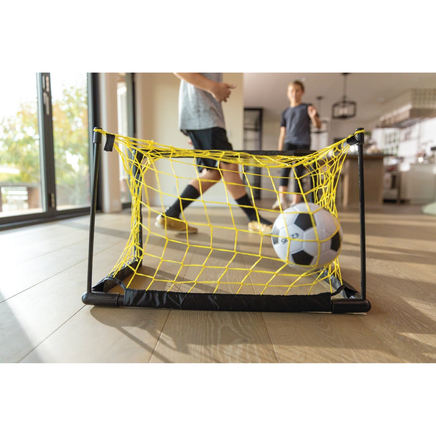 Mini soccer goal captures a ball in a room with children playing indoors