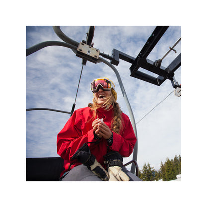 Woman laughs on ski lift wearing goggles at a ski resort on a cloudy day