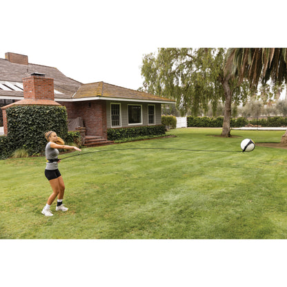 Person pulls a ball on a tether in a backyard lawn