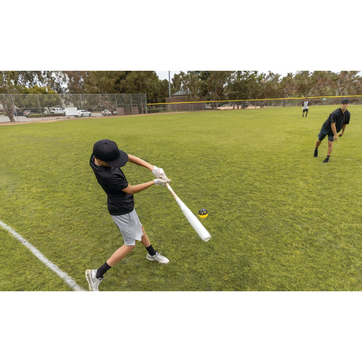 Boy swings bat at ball on baseball field during practice or game outdoors