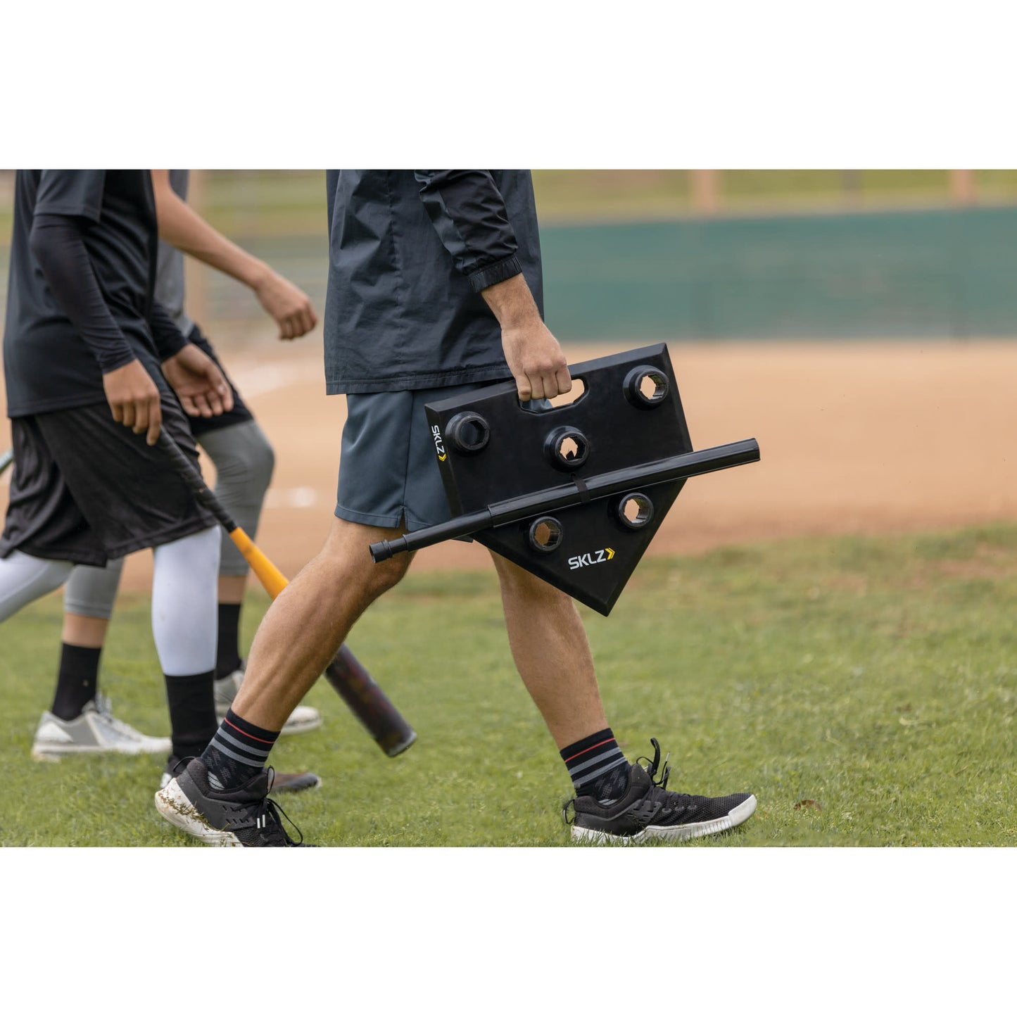 Shot of a man carrying the SKLZ 5-position tee unassembled carrying to practice