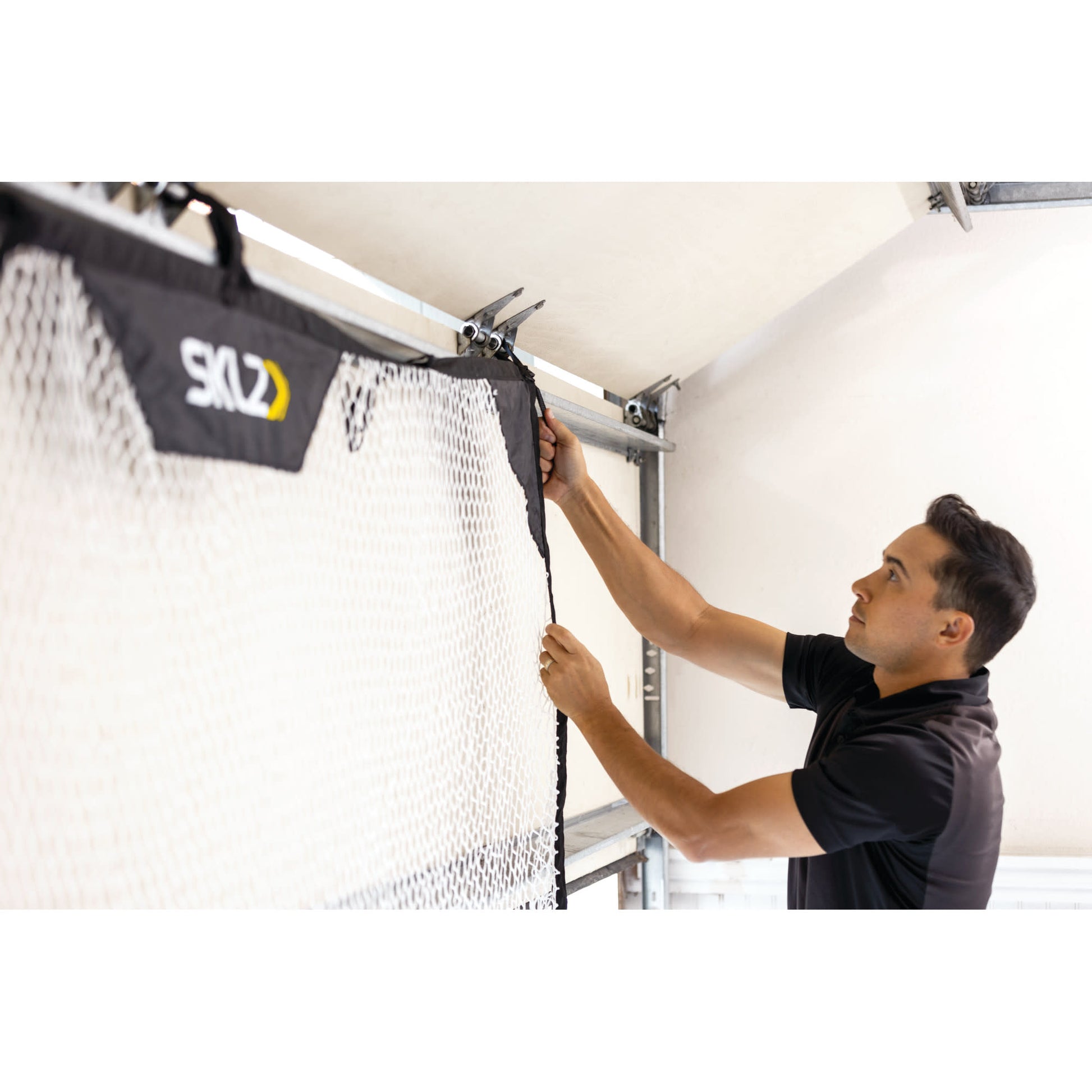 Man installs a net on a garage door for sports or safety purposes