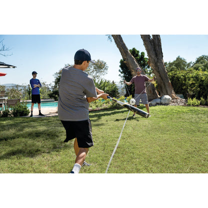 Boy pulls on a rope connected to a drone in a backyard with two men watching