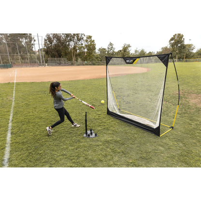 Girl practices hitting a baseball into a net on a baseball field during daytime