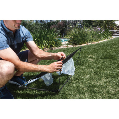 Person sets up a portable insect trap on a grassy lawn in a garden