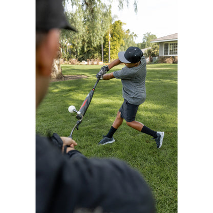 Young boy swings a golf club on a grassy field in a suburban yard.