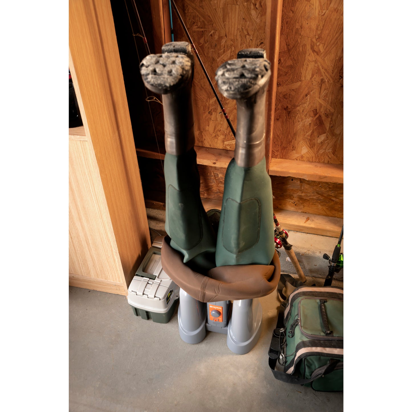 Climbing boots hang upside down on a shoe dryer in a wood-paneled storage area.
