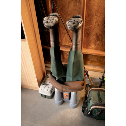 Climbing boots hang upside down on a shoe dryer in a wood-paneled storage area.