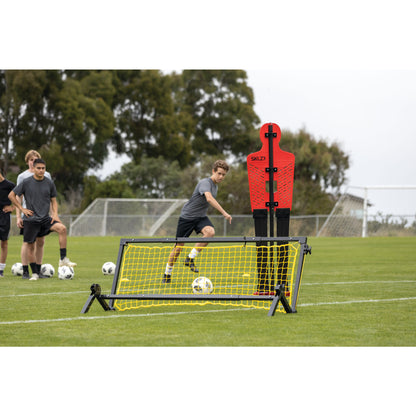 A boy kicks a soccer ball over a training obstacle during a soccer practice on a field
