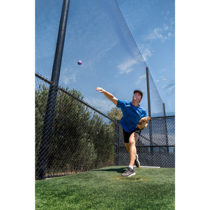 Player throws ball on outdoor baseball field with fence and blue sky background