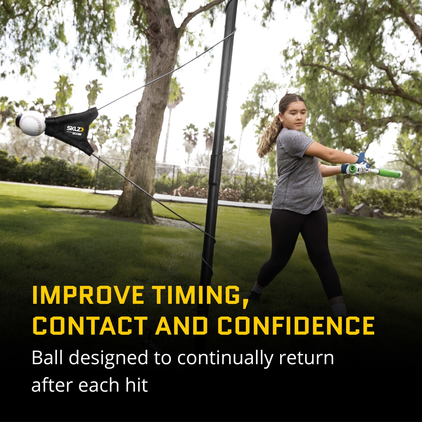 Girl swings a bat at a ball attached to a tether in a park outdoor training area