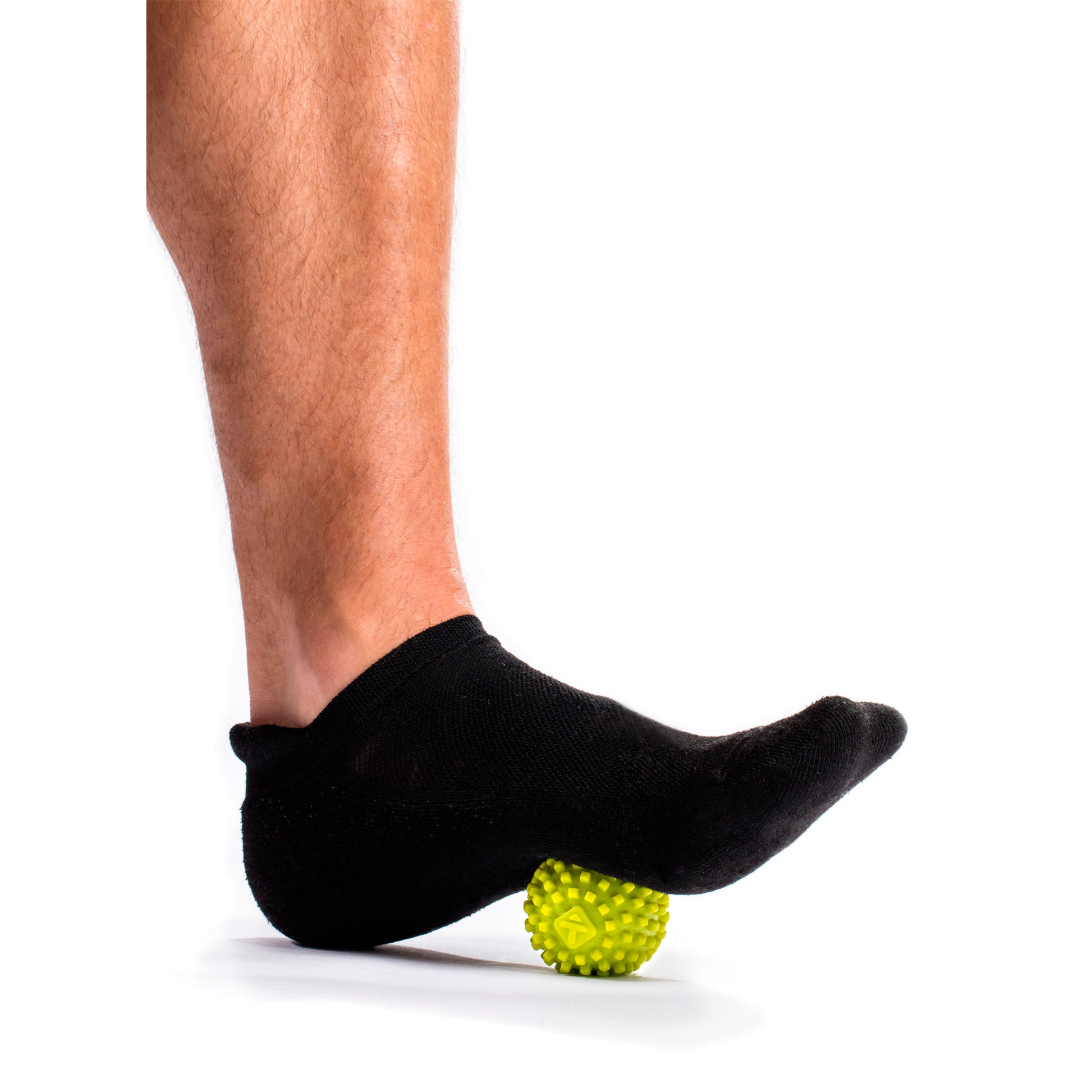 Foot with sock rolls over yellow textured massage ball on a white background.