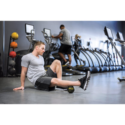 Man rests after working out on the gym floor with workout equipment and cardio machines nearby