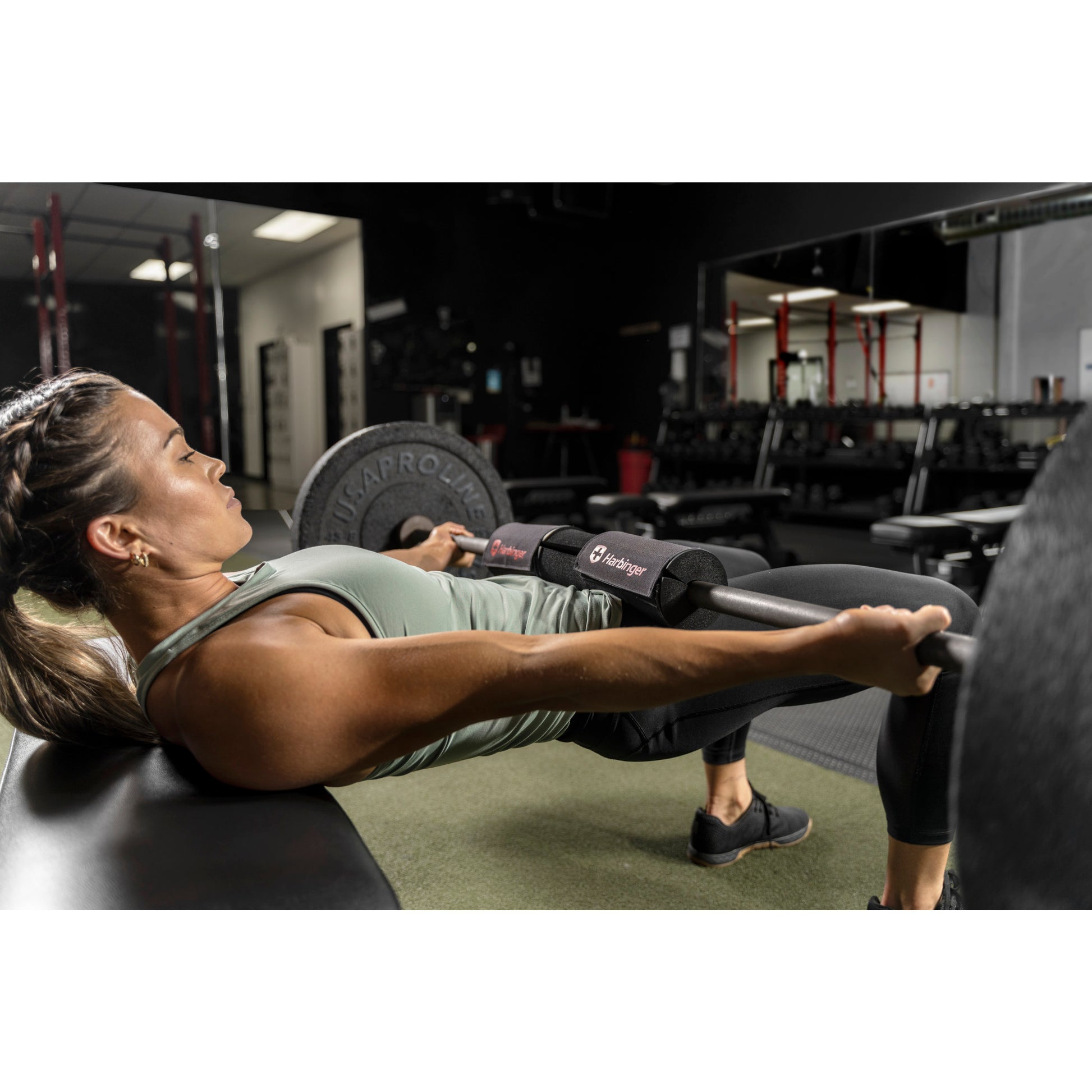 Person lifts barbell with padded support in gym, lying on bench.