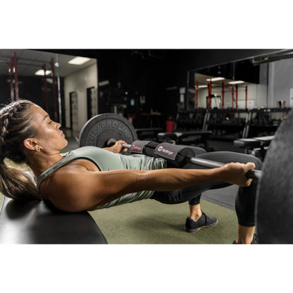 Person lifts barbell with padded support in gym, lying on bench.