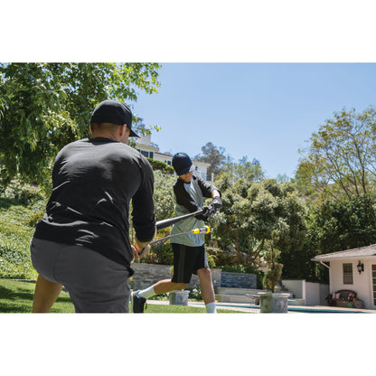 Two people trim bushes using hedge shears in a backyard garden on a sunny day