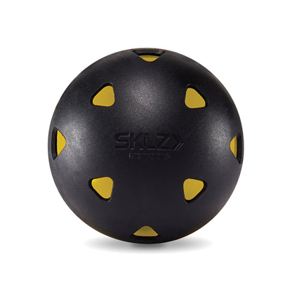 A black balance ball with yellow cutouts rests on a plain white surface