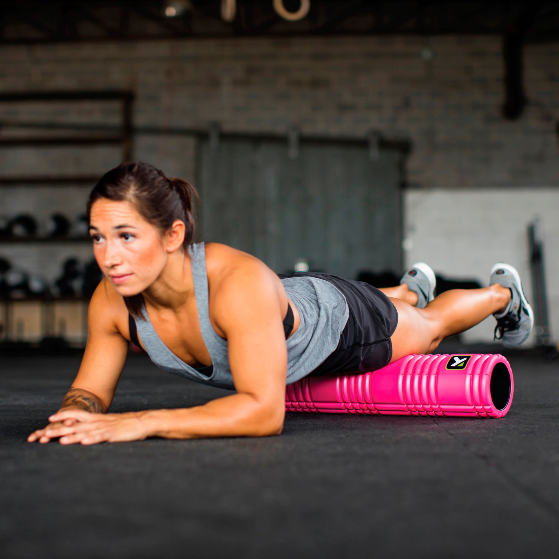 Woman performs a plank exercise on a foam roller in a gym setting