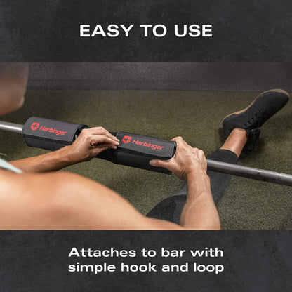 Pad covers gym bar as person secures it with hands on textured mat surface.