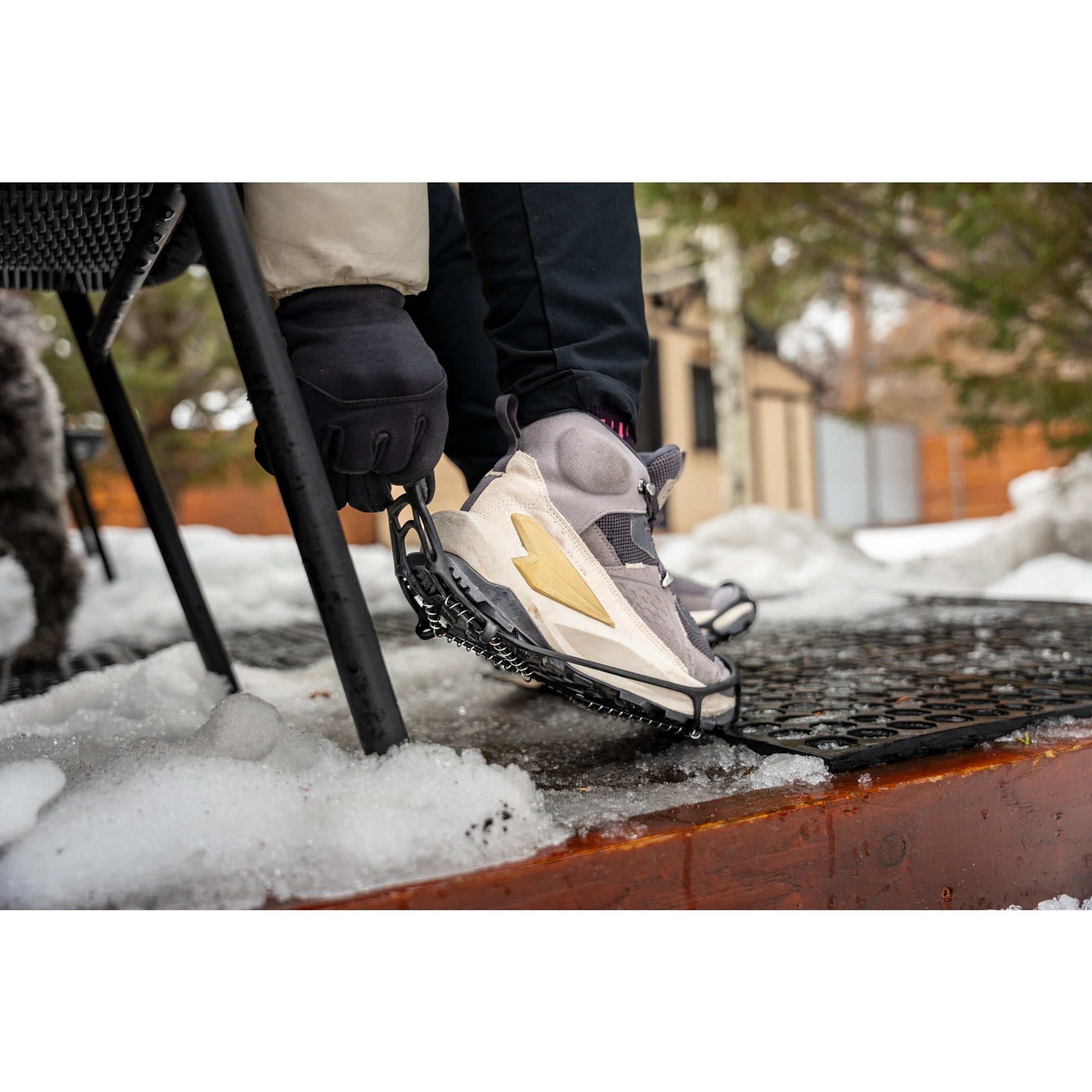 A person is adjusting a snowshoe on their foot outdoors in snowy weather