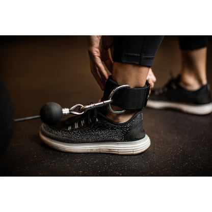 Person secures ankle weight with strap during workout in gym environment