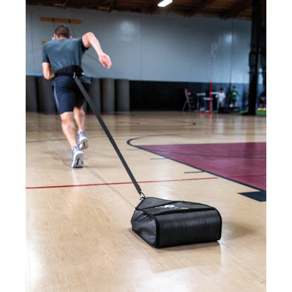 Person pulls rolling bag across gymnasium floor for exercise or transportation