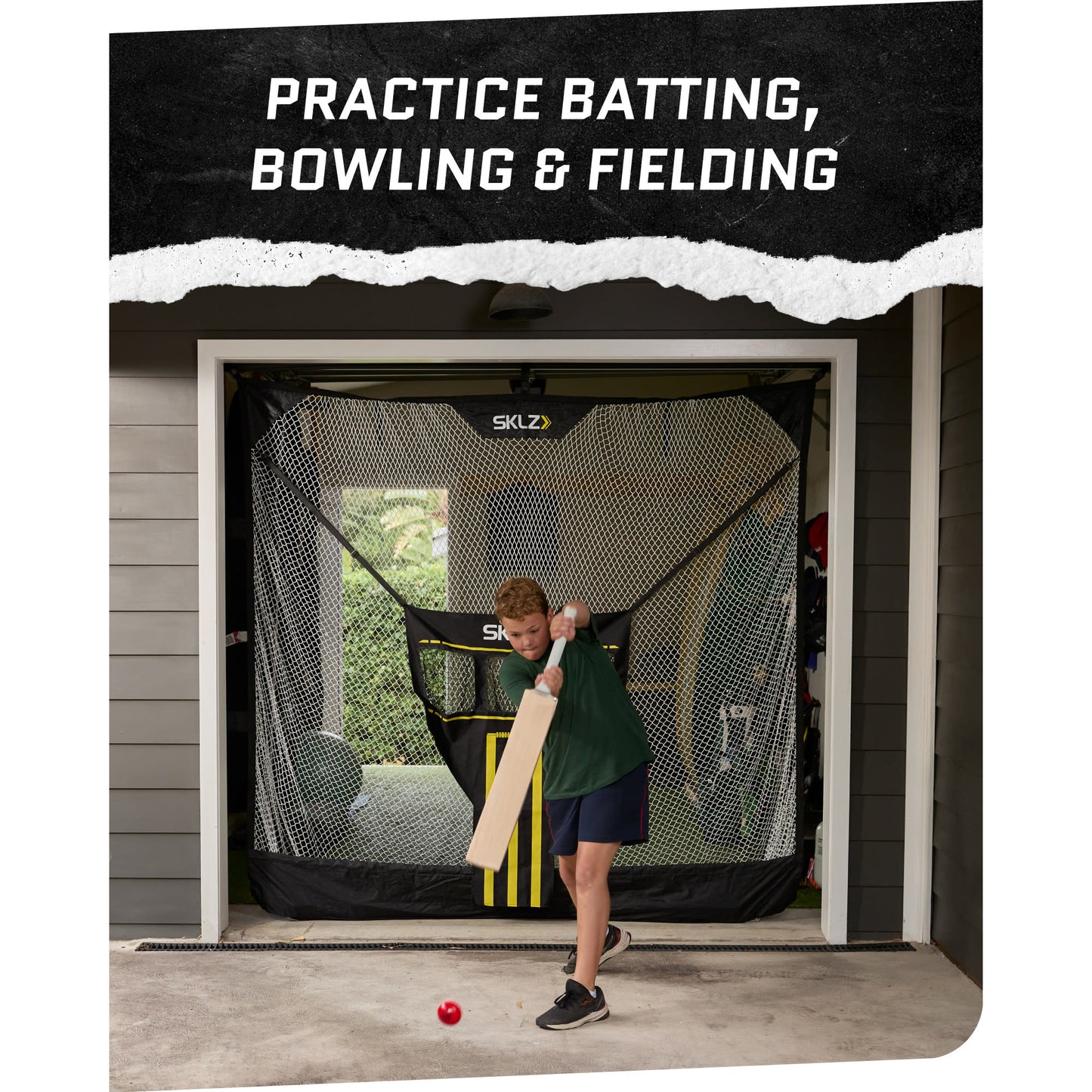 A boy practices batting with a bat in front of a batting cage at home
