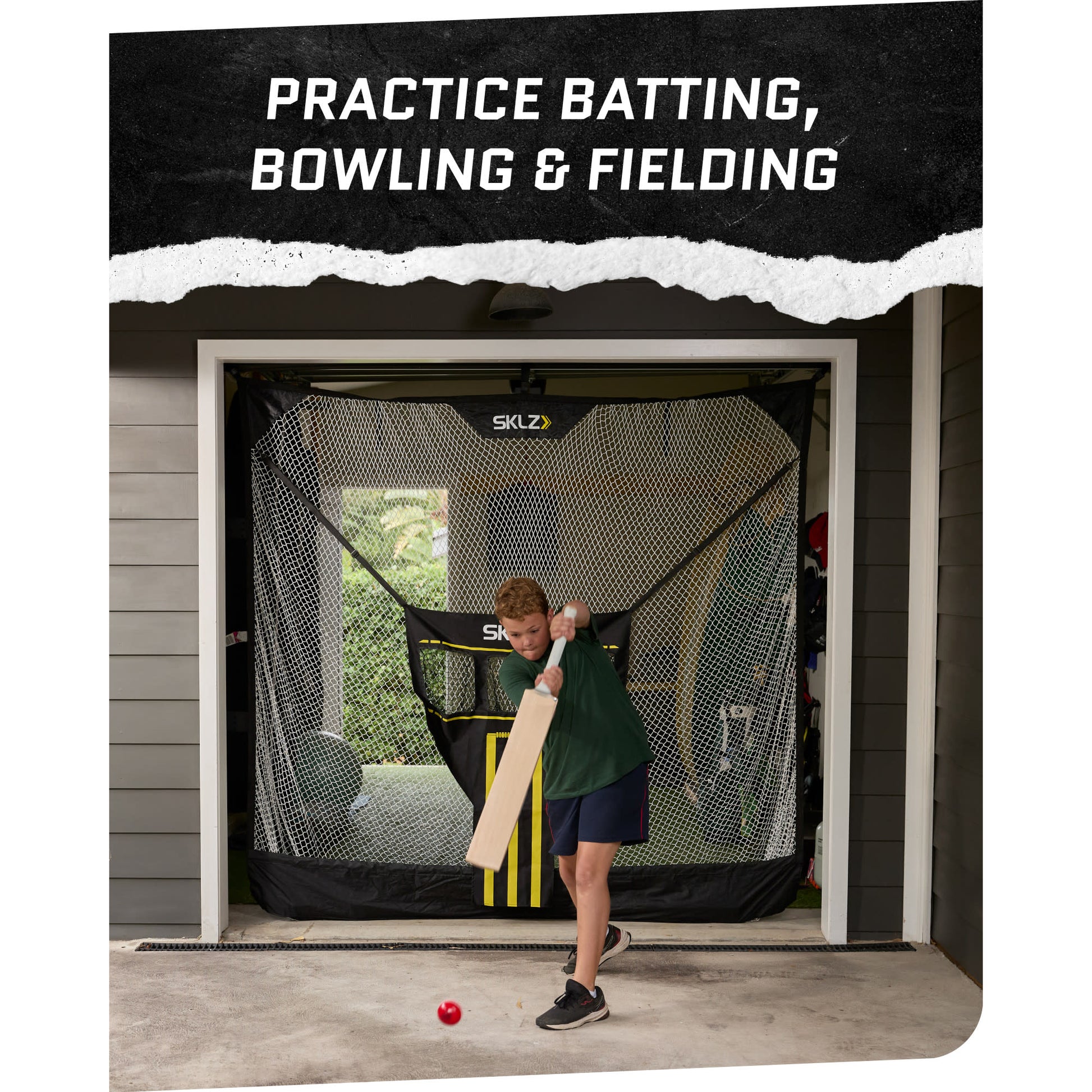 A boy practices batting with a bat in front of a batting cage at home