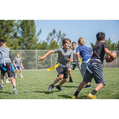 Kids run and chase a football on a grassy field during a game in an outdoor sports area