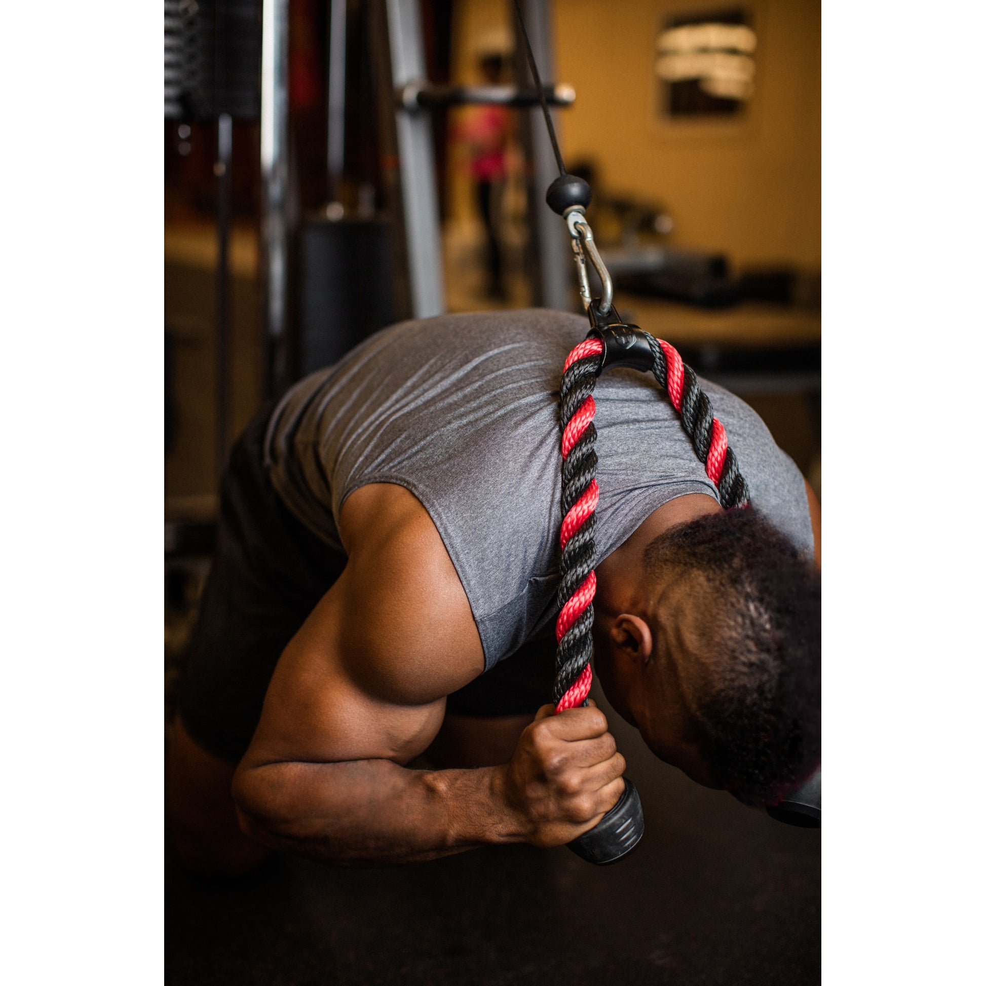 Person kneeling pulls cable rope close in a gym setting.