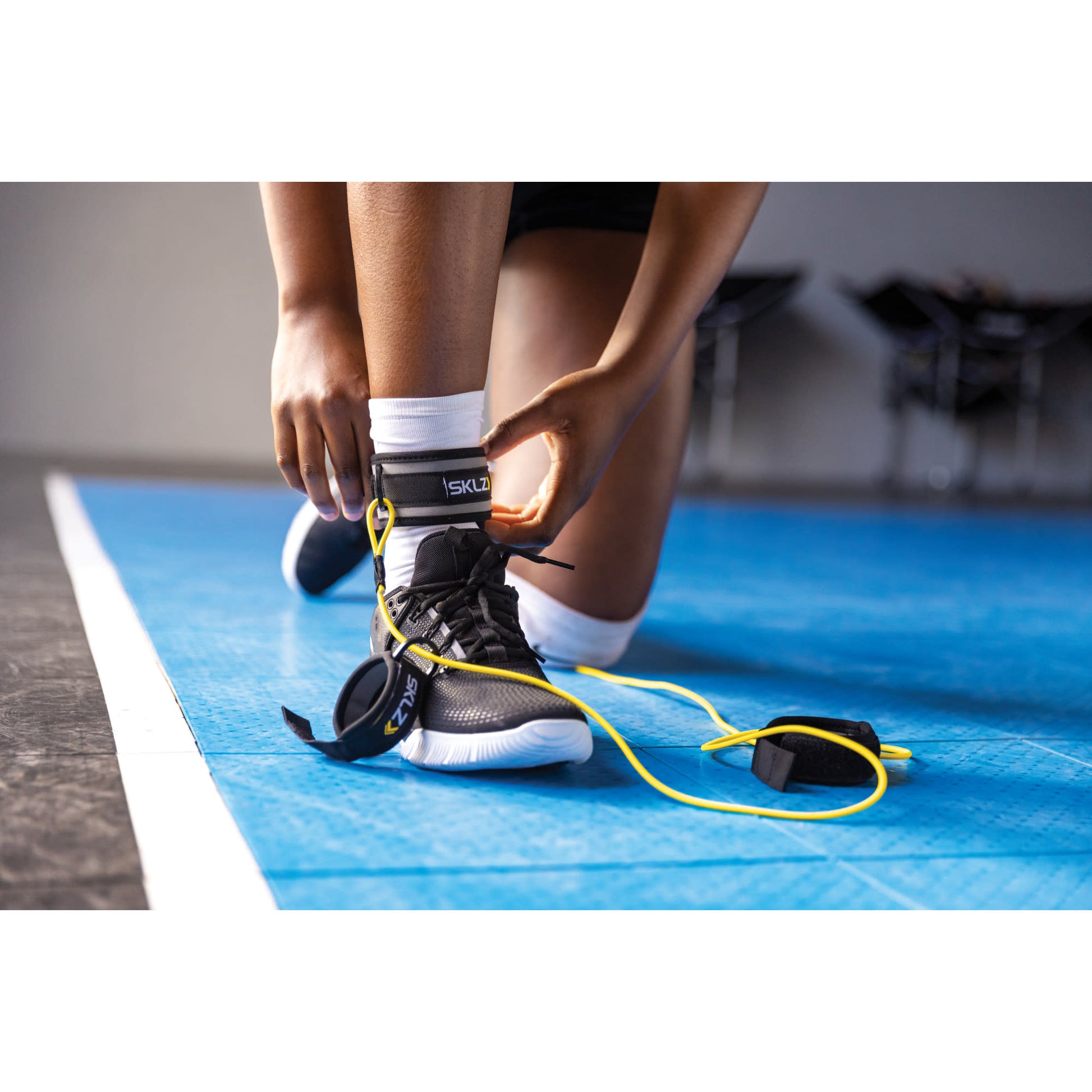 Close-up of SKLZ Bump and Pass trainer on ankle of female in gym