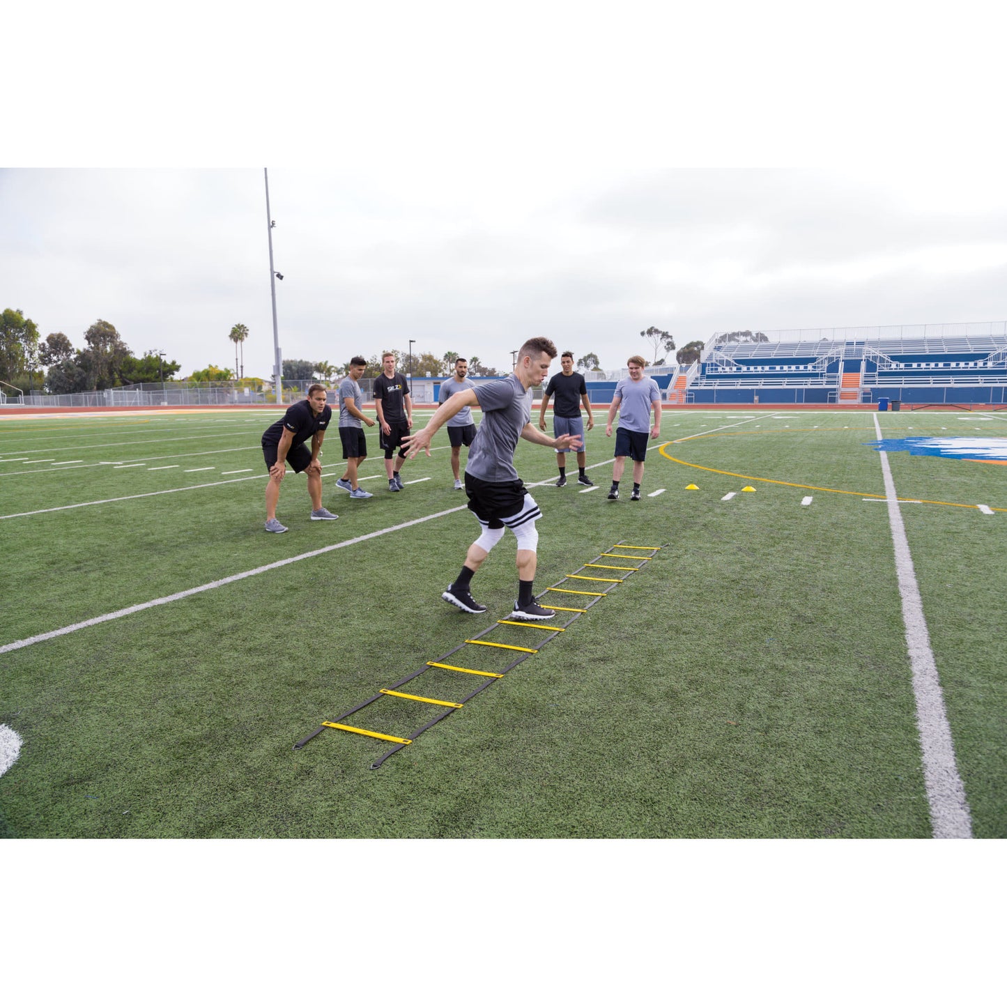 Athletes perform foot agility drills on a football field during training practice session