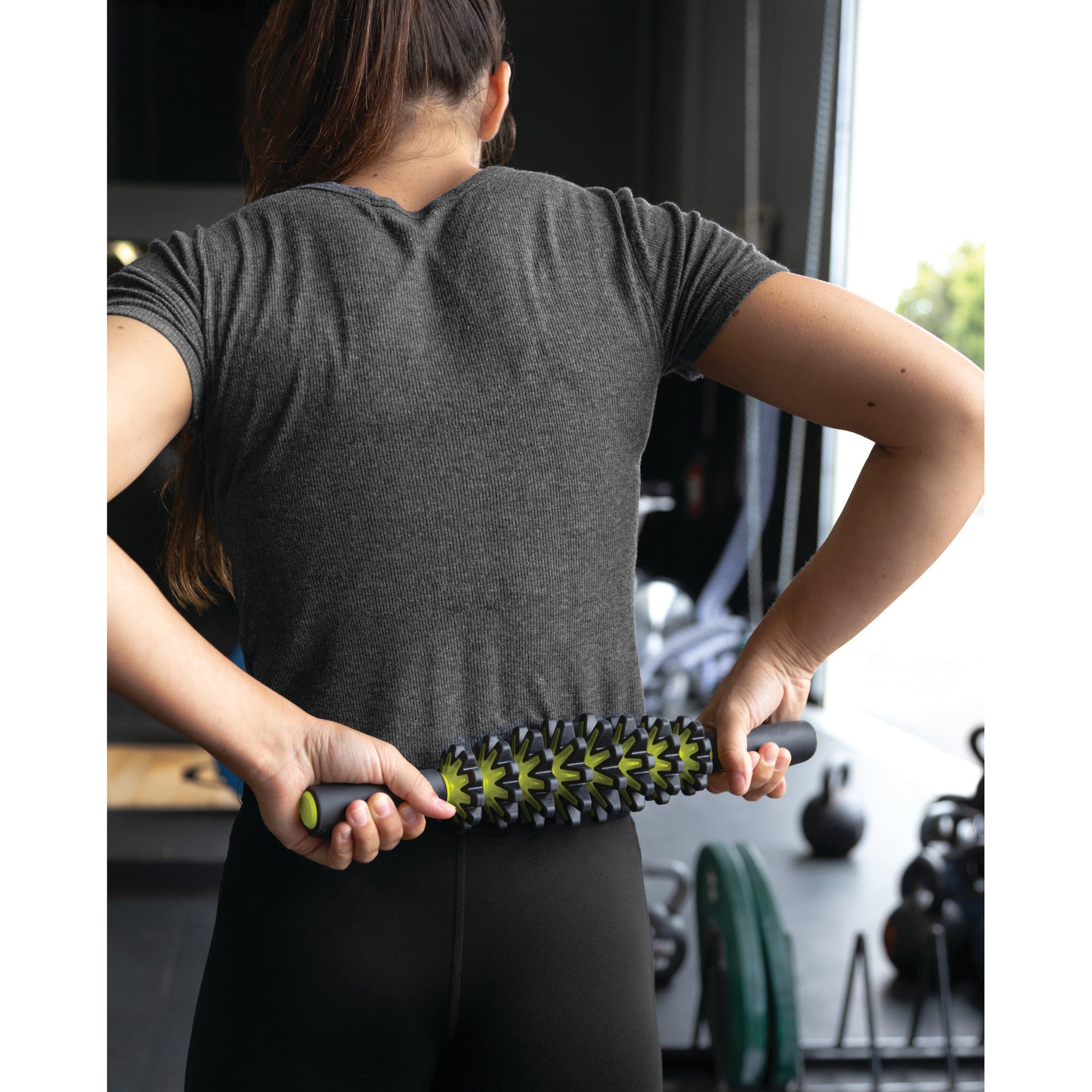 Woman using a foam roller on her back in a gym setting