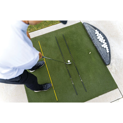 Golfer practices putting on artificial green with putter balls and training aid nearby