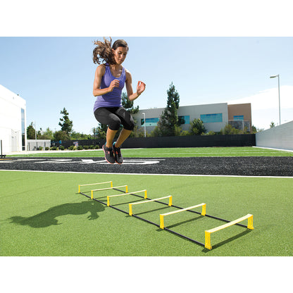 Athletic woman jumps over agility hurdles on a sports field outdoors